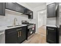 Modern kitchen featuring stainless steel appliances, black cabinets, white backsplash, and a brass-colored faucet at 6446 E Windsor Ln, Norcross, GA 30093