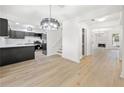 Open-concept kitchen with stainless steel appliances, black cabinets, white marble countertops, and a modern chandelier at 6446 E Windsor Ln, Norcross, GA 30093