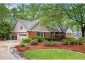 A brick home with an attached garage features well-kept landscaping and a basketball hoop above the garage at 1235 Saint Ives Ct, Suwanee, GA 30024