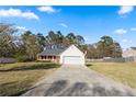 View of a single-story home with a long driveway, two-car garage, and spacious front yard at 704 Manor Ridge Dr, Loganville, GA 30052