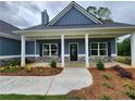 Inviting front porch with stone accents, landscaping, and a stylish entry door on a blue home at 476 Benson Meadows Dr, Dallas, GA 30157
