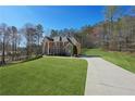 Large brick home featuring a long driveway, lush lawn, and a backdrop of trees at 5615 Toccoa Dr, Douglasville, GA 30135