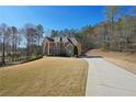 Large brick home featuring a long driveway, well-maintained lawn, and a backdrop of trees at 5615 Toccoa Dr, Douglasville, GA 30135