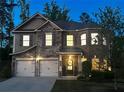 Charming two-story home with stone and brick facade, well-manicured lawn, and attached two-car garage at night at 406 Dunaway Ct, Grayson, GA 30017
