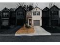 Daytime view of charming townhomes with gray garage doors, paved driveways, and professionally landscaped lawns at 3132 Meadowstone Sw Ln, Atlanta, GA 30331