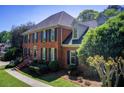 Side view of a brick two-story home featuring manicured shrubs and a walkway at 5162 Charlemagne Sw Way, Lilburn, GA 30047