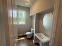 Stylish half bathroom with pedestal sink, oval mirror, and a window with a view at 315 Lakeside Ct, Canton, GA 30114