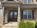 Inviting front entrance with double doors, brick facade, stone pillars, and lush landscaping at 5530 Lacebark Pine Ct, Cumming, GA 30040