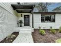 Inviting entryway with a black front door, painted brick, and lush landscaping creating curb appeal at 1450 Cedarhurst Dr, Dunwoody, GA 30338