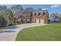 Beautiful brick home boasts a three-car garage and a lush green lawn, perfect for outdoor enjoyment at 6925 Lighthouse Point, Cumming, GA 30041