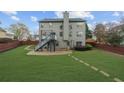 Expansive backyard featuring a spacious lawn, charming stone fire pit, and elevated deck at 5280 Oak Hill Ter, Cumming, GA 30040