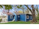 Blue cottage-style home featuring white trim, side yard access, and mature trees at 5074 Park Ave, Forest Park, GA 30297