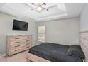 Cozy bedroom with neutral walls, carpet, TV, ceiling fan, dresser, and a comfortable black bed at 7847 Wrotham Cir, Atlanta, GA 30349