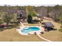 Resort style backyard with an in-ground pool, covered seating area, lush landscaping, and mature trees at 8906 E Carroll Rd, Winston, GA 30187