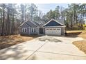 Inviting gray home with stone accents, long driveway, and a two-car garage nestled in a wooded area at 5328 Monticello Dr, Villa Rica, GA 30180