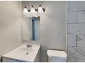 Bathroom featuring a white sink, toilet, light fixture and tile, plus a large mirror at 908 Kennesaw Dr, Forest Park, GA 30297