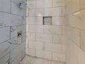 Close up of shower with marbled tile walls, recessed shelf and grey penny tile floor at 908 Kennesaw Dr, Forest Park, GA 30297
