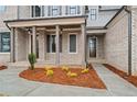 Charming covered front porch with brick columns and meticulous landscaping with flowering plants at 3812 Havenrock Dr, Marietta, GA 30066
