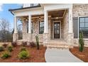 Inviting front porch featuring brick columns, wood ceiling, elegant lighting, and professional landscaping at 3816 Havenrock Drive, Marietta, GA 30066