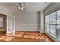 Sunlit living room with hardwood floors, white wall paneling, a ceiling fan, and a doorway that leads to another room at 1824 Kristen Ct, Suwanee, GA 30024