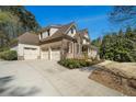 View of the home's three-car garage, long driveway, manicured lawn, and the beautiful architectural details at 3227 Aviary Nw Ct, Acworth, GA 30101