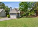 Home's side exterior and garage with lush green lawn and mature trees at 1904 Woodland Hills Nw Ave, Atlanta, GA 30318