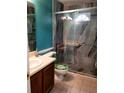 Bathroom featuring granite tiled shower with glass doors, teal accent wall, and wooden vanity at 1034 Bettina Ct, Mableton, GA 30126