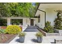 Modern home with updated landscaping and a sleek entryway design with an outdoor sitting area at 240 W Spalding Dr, Sandy Springs, GA 30328