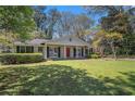 Charming single-story home with a well-manicured lawn, a red front door and a covered front porch at 2992 Westminster Nw Cir, Atlanta, GA 30327