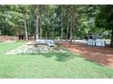 Expansive backyard featuring a stone patio with outdoor seating and a built-in grill, surrounded by mature trees at 1585 Elliott Rd, Mcdonough, GA 30252