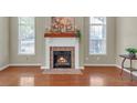 Living room with a brick fireplace, hardwood floors, and light-filled windows with a traditional mantel at 206 Glens Loop, Woodstock, GA 30188