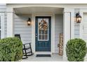 Inviting front entrance with a decorative wreath, a rocking chair, and manicured bushes at 6350 Lantana Village Way, Cumming, GA 30028