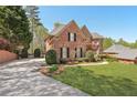 Spacious brick home with an expansive front lawn, long driveway, mature trees, and meticulous landscaping at 4215 Homestead Ridge Dr, Cumming, GA 30041