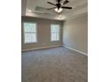 Bright main bedroom with a tray ceiling, ceiling fan and two windows offering wooded views at 95 Kendall Ln, Covington, GA 30014