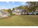 Charming brick home with a manicured lawn, elegant white columns, and mature trees in a serene setting at 4385 Old Hamilton Mill Rd, Buford, GA 30518