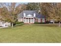 Picturesque brick home with elegant columns, lush greenery, and a sprawling lawn surrounded by colorful autumn trees at 4385 Old Hamilton Mill Rd, Buford, GA 30518