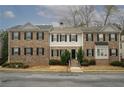 Street-level view of a row of brick townhouses with black shutters and well-maintained landscaping at 5980 Eagle Tiff Ln, Sugar Hill, GA 30518