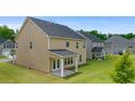 Backyard view of a tan two-story home with covered patio and large grassy yard at 13562 Whitman Ln, Covington, GA 30014