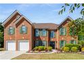 Charming brick home with green shutters, manicured landscaping, and a spacious driveway with a large three-car garage at 308 Paper Woods Dr, Lawrenceville, GA 30046