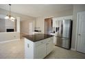 Open-concept kitchen featuring a stainless steel refrigerator, center island with granite countertop, and tile flooring at 3936 Toccoa Falls Dr, Duluth, GA 30097
