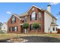 Inviting two-story brick home with a manicured front yard and classic architectural design, set on a sunny day at 130 Arbor Cove Way, Stockbridge, GA 30281