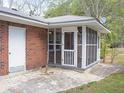 View of a brick home with a screened-in porch and adjoining concrete patio at 130 Scarlet Dr, Jonesboro, GA 30236