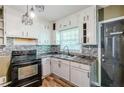 Functional kitchen featuring white cabinets, wood flooring, and modern lighting fixture at 1239 Avonwood Sw Cir, Atlanta, GA 30311