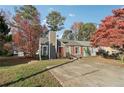 Charming home featuring a chimney, red door, and orange shutters complemented by a large front yard and concrete driveway at 7020 Panda Ln, Austell, GA 30168