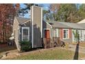 Charming home featuring a chimney, red door, and orange shutters complemented by a lush, landscaped yard at 7020 Panda Ln, Austell, GA 30168
