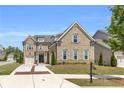 A stately brick home featuring a manicured lawn, three car garage, and brick-lined driveway at 6210 Bellmoore Park Ln, Duluth, GA 30097