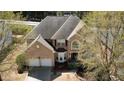 Aerial view of a two-story brick home, with a two-car garage, surrounded by mature trees and landscaping at 2688 Autumn Ridge Ln, Lawrenceville, GA 30044