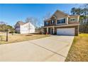 Well-manicured lawn and two-story home with driveway leading to a two-car garage at 4870 Odum View Ln, Cumming, GA 30040