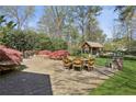 Stone patio with outdoor dining area and fire pit, surrounded by lush landscaping at 710 E Northway Ln, Atlanta, GA 30342