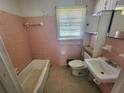 Small pink-tiled bathroom featuring a bathtub, toilet, and vanity at 103 Woodhaven Dr, Stockbridge, GA 30281